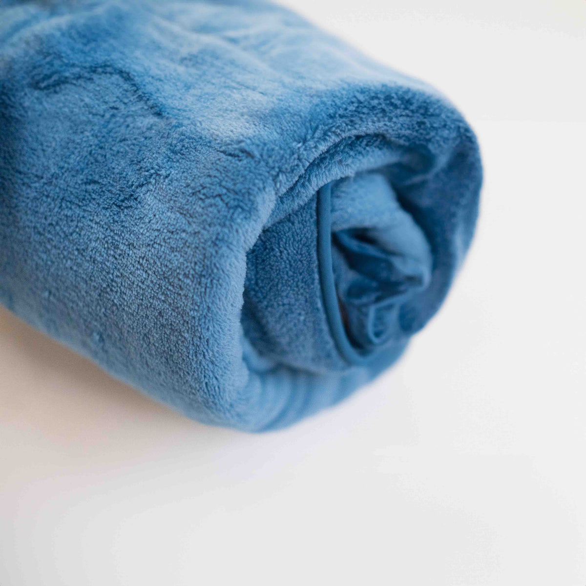 Le peignoir Ocean Breeze Dog Towel Robe bleu, roulé en un paquet compact.